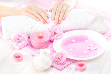 Obraz na płótnie Canvas beautiful pink manicure with tea rose on the white wooden table. spa