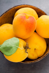 Fresh apricots in wooden bowl on old rustic background.