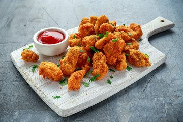 Fried crispy chicken nuggets with ketchup on white board