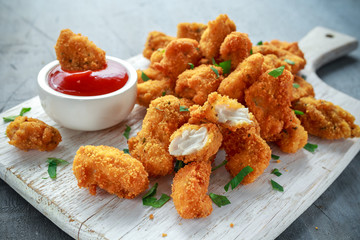 Fried crispy chicken nuggets with ketchup on white board