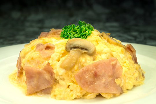Omelet with ham and mushroom on rice in white dish 