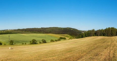 Fototapeta na wymiar Panorama of a hilly forested landscape near the town of Tisnov in the Czech Republic. A sunny morning in the pasture.