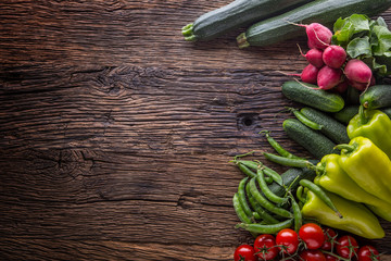 Vegetable.Fresh vegetable tomato radish green pepper peas zucchini and cucumber on rustic oak table.