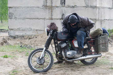 Fototapeta na wymiar A post apocalyptic man on motorcycle near the destroyed building