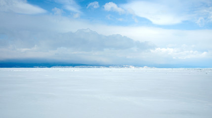 beautiful views of Lake Baikal, covered with ice. Snow-capped mountains on the horizon. Sunny day. Photo partially tinted.