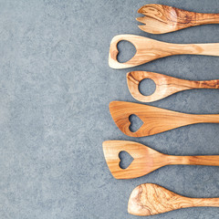 Various wooden cooking utensils border. Wooden spoons and wooden spatula on dark stone background...
