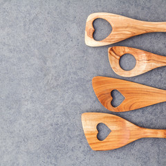 Various wooden cooking utensils border. Wooden spoons and wooden spatula on dark stone background with flat lay and copy space.