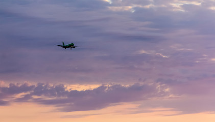 Fototapeta na wymiar passenger plane flies high in the sky in the rays of the sunset goes on landing