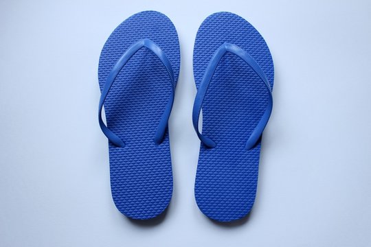 Des paires de chaussures de plage tong en couleurs sur fond blanc