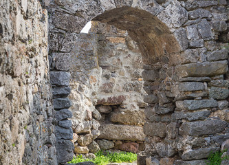 arch of gray stone old building way out of it on a stone masonry labyrinth amid the ruins