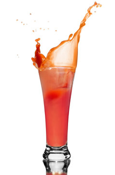 a slice of tomato drops into a glass of juice, squirt of tomato juice