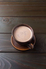 Hot chocolate or cocoa drink in clay cup, on dark brown wooden table