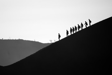 A group of friends descending Mt. Bromo in morning mist. Mt. Bromo is one of the most visited...