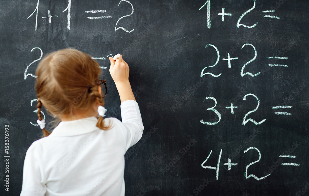 Wall mural Happy schoolgirl preschool girl with book near school blackboard