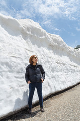 Fototapeta na wymiar Female traveler and snow wall at japan alps tateyama kurobe alpine route