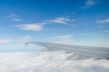 Wing of airplane flying above the cloud
