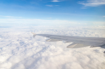 Fototapeta na wymiar Wing of airplane flying above the cloud