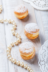 Obraz na płótnie Canvas Profiterole or cream puff cakes filled with whipped cream on wooden background close up. Delicious dessert with decor