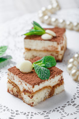 Mini cakes tiramisu with white chocolate, cocoa and candies on light background close up. Delicious dessert