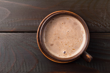 Boisson au chocolat chaud ou au cacao dans une tasse en argile, sur une table en bois marron foncé, vue de dessus