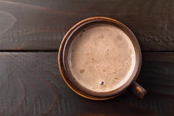 Photo sur Plexiglas Chocolat Boisson au chocolat chaud ou au cacao dans une tasse en argile, sur une table en bois marron foncé, vue de dessus