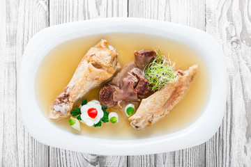 Homemade jelly chicken decorated with greens and eggs on plate on wooden background close up. Cold Meat Dishes