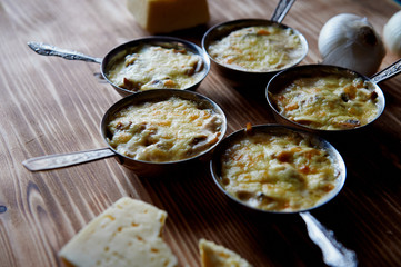 Several zhuleny of mushrooms baked in cream with cheese.In the iron cocotte.