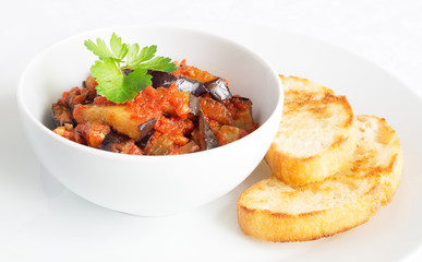 a bowl of eggplant with tomato sauce and fried bread
