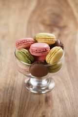 assorted macarons in glass bowl on wood table, with copy space