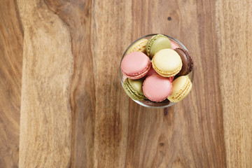 assorted macarons in glass bowl on wood table from above, with copy space