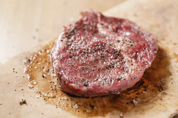 seasoned raw rib eye steak on board closeup, shallow focus