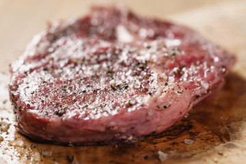 raw rib eye steak on board closeup, shallow focus