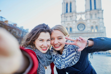 Two young girls taking selfie near Notre-Dame in Paris