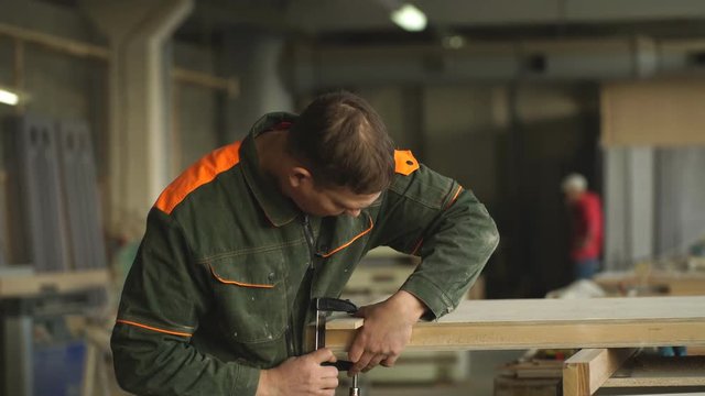 Worker grinds the wood of angular grinding machine