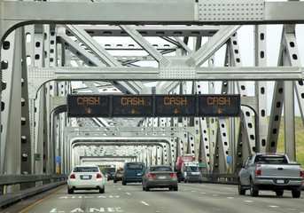 CASH ONLY toll information sign attached to truss bridge with traffic.