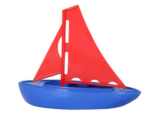Isolated plastic toy sailboat with red sails and blue hull.