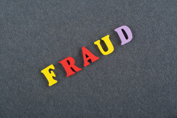 FRAUD word on black board background composed from colorful abc alphabet block wooden letters, copy space for ad text. Learning english concept.