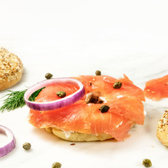Making lox bagels, on white marble background with copyspace