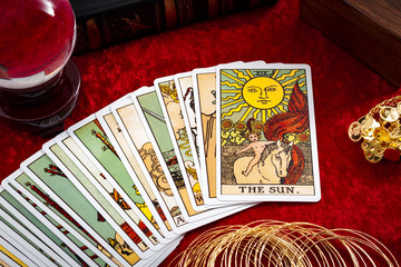 Fortune teller and whitcraft concept with tarot cards spread on red velvet surrounded by a magic...