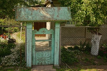 Старая синяя калитка и забор из сетки перед сельским домом