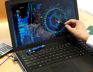 engineer working on computer at the design of mechanical piece