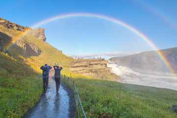 A couple enjoying the amazing Gullfoss waterfall with rainbow, Iceland