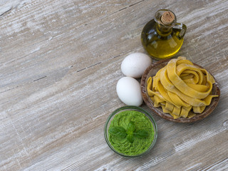 Homemade green pesto sauce and basil on a wooden board. 