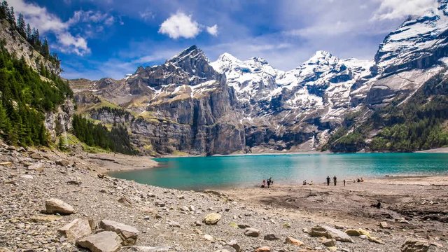 Amazing tourquise Oeschinnensee lake with waterfalls, wooden chalet and Swiss Alps, Berner Oberland, Switzerland. 
