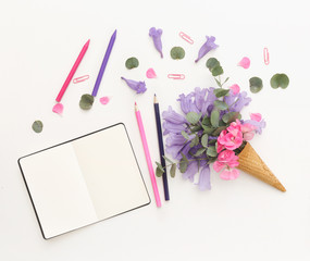 Creative still life with notebook and ice cream waffle cone with flowers . Flat lay, top view, copy space