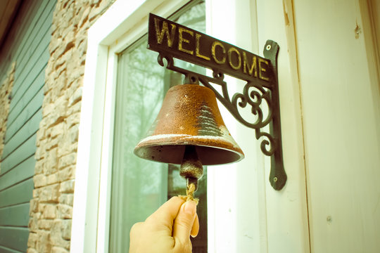 A large bell next to the door, replacing the doorbell. the bell Welcome. Ring the bell..