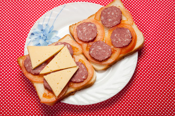 Toast with sausage and cheese on a plate on a red table