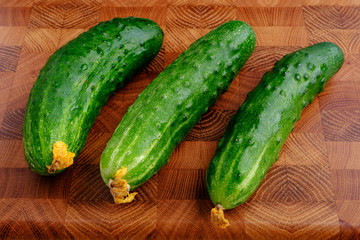 fresh green cucumbers on wooden cutting board close-up
