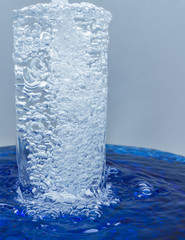 A glass of water, water with bubbles overflows through glass