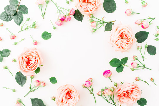 Frame made of pink roses, buds and leaves on white background. Flat lay, top view. Floral background.